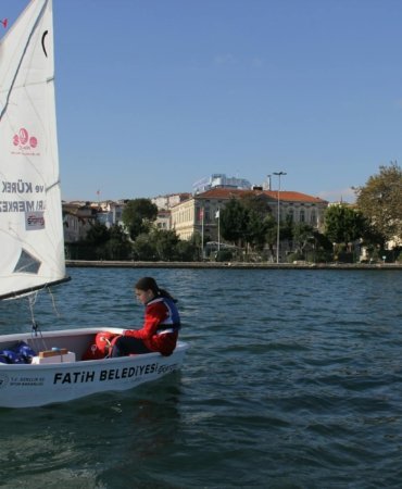 A young person sailing in a small boat on the waters of İstanbul, enjoying a sunny day.
