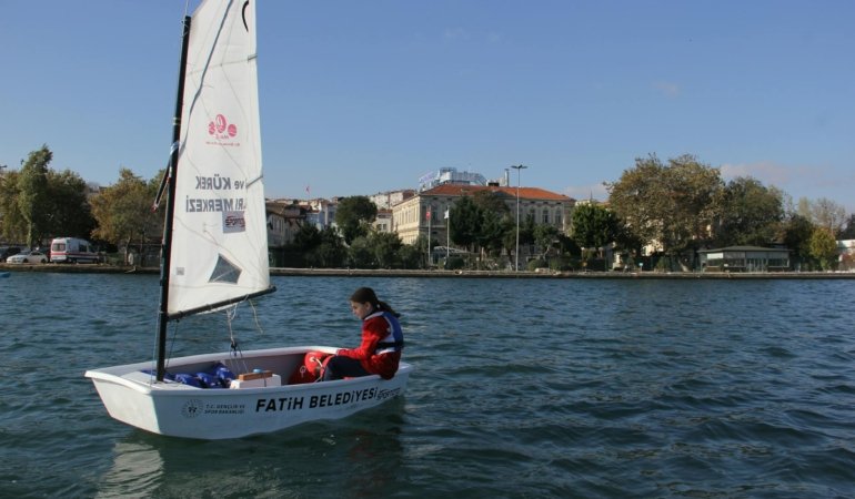A young person sailing in a small boat on the waters of İstanbul, enjoying a sunny day.