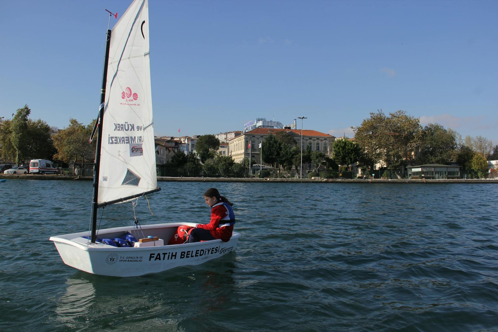 A young person sailing in a small boat on the waters of İstanbul, enjoying a sunny day.
