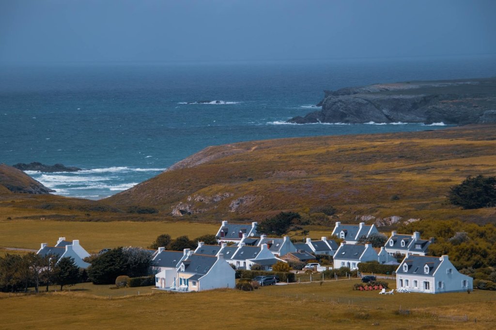 A serene view of a picturesque village along the Brittany coast in France, overlooking the sea.