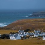 A serene view of a picturesque village along the Brittany coast in France, overlooking the sea.